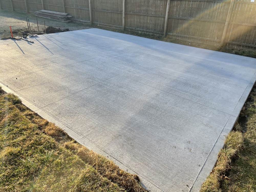 Large concrete patio pad installed in a fenced backyard by South Jersey Construction Enterprise